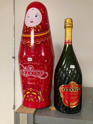 une bouteille de champagne et une poupée matriochka posées sur une étagère