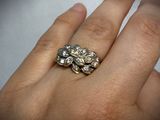 a woman ' s hand holding a gold ring with flowers on it