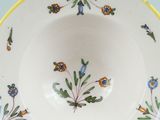 a white bowl with a yellow rim and blue flowers on it