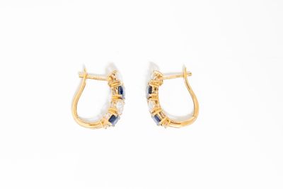 une paire de boucles d'oreilles créoles en or et saphir sur fond blanc