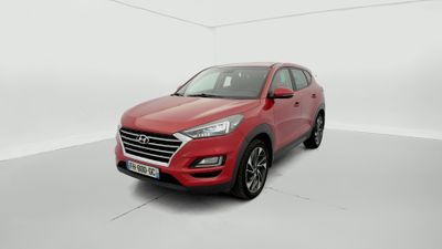 une Hyundai Tucson rouge de 2019 garée dans une pièce blanche