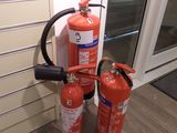 two fire extinguisors attached to the side of a window