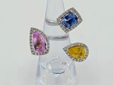 three different colored sapphire and diamond rings on a clear glass stand
