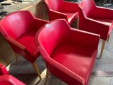 Plusieurs chaises rouges sont alignées en rang dans une pièce
