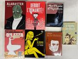 plusieurs livres posés sur une surface blanche, avec une personne en arrière-plan