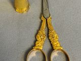 a pair of scissors and a thimble on a table