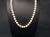 un collier de perles blanches et une boîte noire sur fond noir