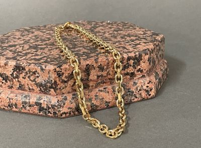 a gold chain that is laying on top of a rock