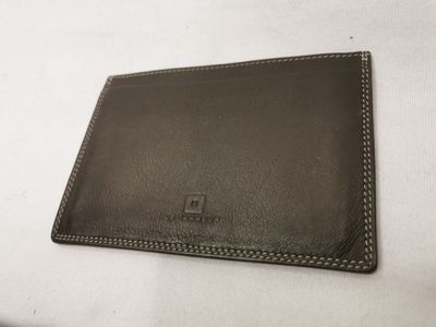un gros plan d'un portefeuille posé sur un lit recouvert d'un drap blanc