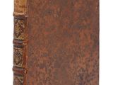 un vieux livre à la couverture brune posé sur une surface blanche