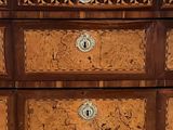 a wooden chest of drawers with marble top on a hard wood floor