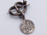 a silver snake and a coin on a white surface
