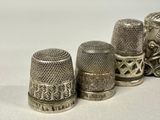 three silver thimbles are lined up in a row on a white surface