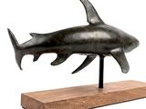 statue of a shark on a wooden base on a white background