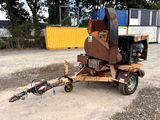 a trailer with a machine attached to it that is parked in the dirt