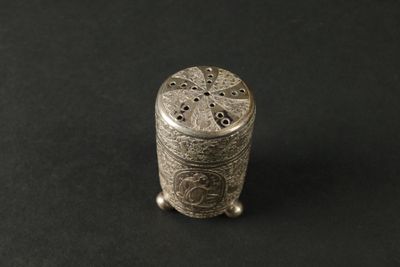 une vieille salière en argent posée sur une surface noire