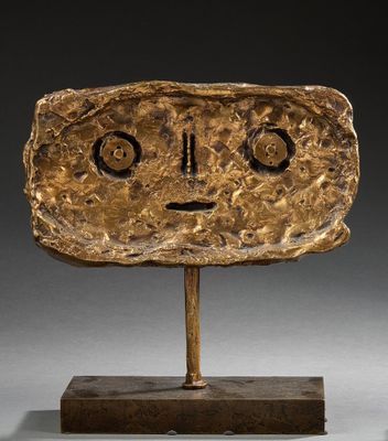 a close up of a sculpture of a face on a wooden base