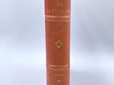 an old red book sitting on top of a white table