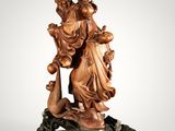 a wooden statue of a woman holding a child on a rock