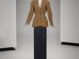mannequin vêtu d'une veste marron et d'une jupe noire dans une pièce blanche