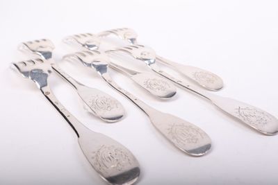 six spoons and a fork are sitting on a white surface