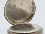 a silver pocket watch sitting on a white surface