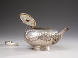 a silver teapot with a lid on a table