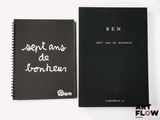 two black notebooks with white writing on them sitting next to each other