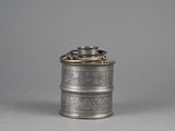 an old silver metal canister with a metal lid on a grey background