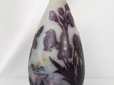 a white vase with purple flowers on it sitting on a table