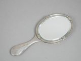 a small mirror with a silver handle on a table