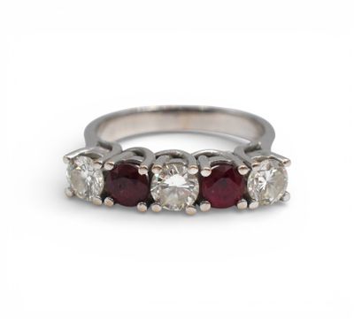 a white gold ring with five round cut diamonds and a red ruby stone