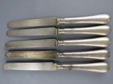 six silverplated knives with handles and handles on a table