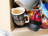 many cups and mugs in a box on the floor