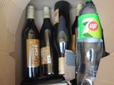 a cardboard box filled with bottles of wine and a can of soda