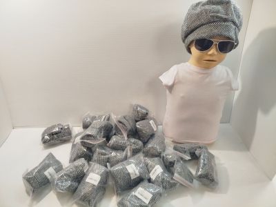 un mannequin portant un chapeau et des lunettes de soleil, à côté d'une pile de sacs en plastique