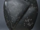 a black stone sculpture sitting on top of a wooden base