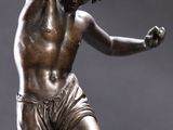 bronze statue of a man holding a tennis racquet on a marble base