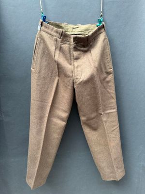 beige pants hanging on a clothes line against a blue wall