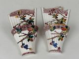 pair of white vases decorated with flowers and vines on a white surface