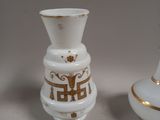 two white vases with gold designs sitting next to each other