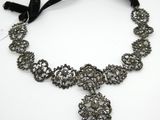 un gros plan d'un collier posé sur une surface blanche, avec un ruban noir