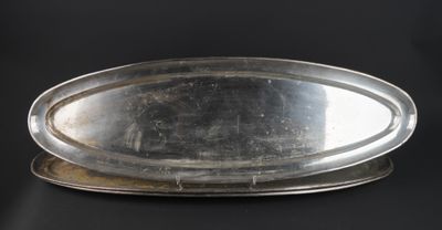 an oval silver tray on a black background with a black background