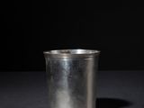 a metal cup sitting on a table with a black background