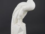 sculpture of a white peacock sitting on a rock on a black background