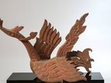 une sculpture représentant un oiseau perché sur un socle noir