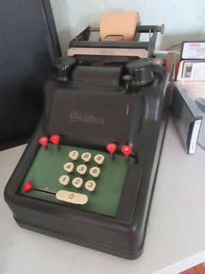 une vieille machine à écrire posée sur un bureau, à côté d'un ordinateur portable