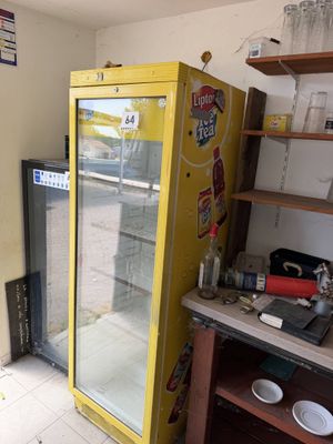 a refrigerator in the corner of a room with a lot of clutter on it