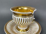 a white and gold cup and saucer on a saucer