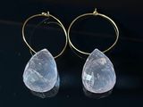 paire de boucles d'oreilles en quartz transparent avec des anneaux dorés sur fond noir